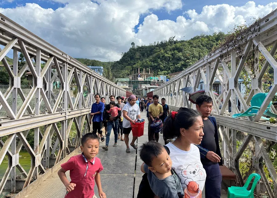 People who fled Myanmar carry their belongings across a bridge that connects Myanmar and India at the border village of Zokhawthar, Champhai district, in India's northeastern state of Mizoram, India, on 15 November 2023. (Chanchinmawia/Reuters)