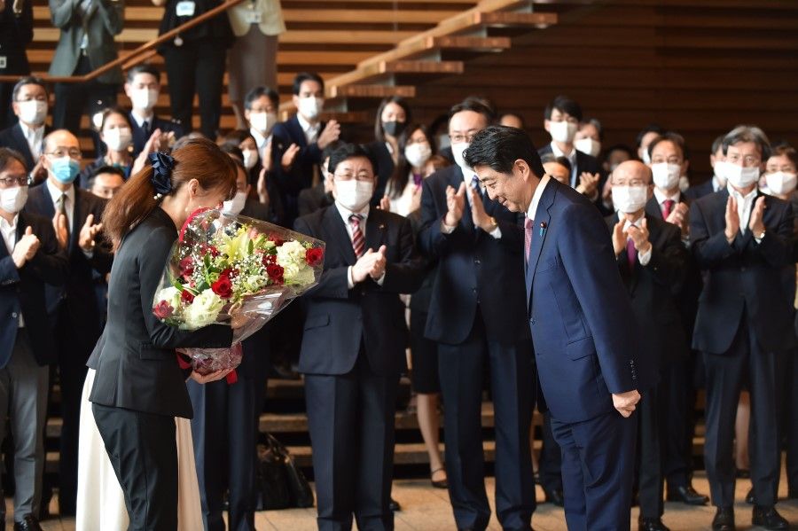 Japan's outgoing Prime Minister Shinzo Abe (C-R) receives flowers from the staff after his last cabinet meeting at prime minister's office in Tokyo on 16 September 2020. (Kazuhiro Nogi/AFP)