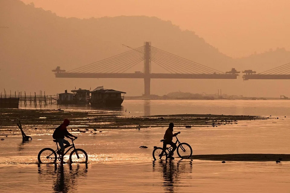Children riding bicycles along the banks of the Brahmaputra river, a transboundary river also known as the Yarlung Zangbo in Tibet, on 31 December 2024. (Biju Boro/AFP)
