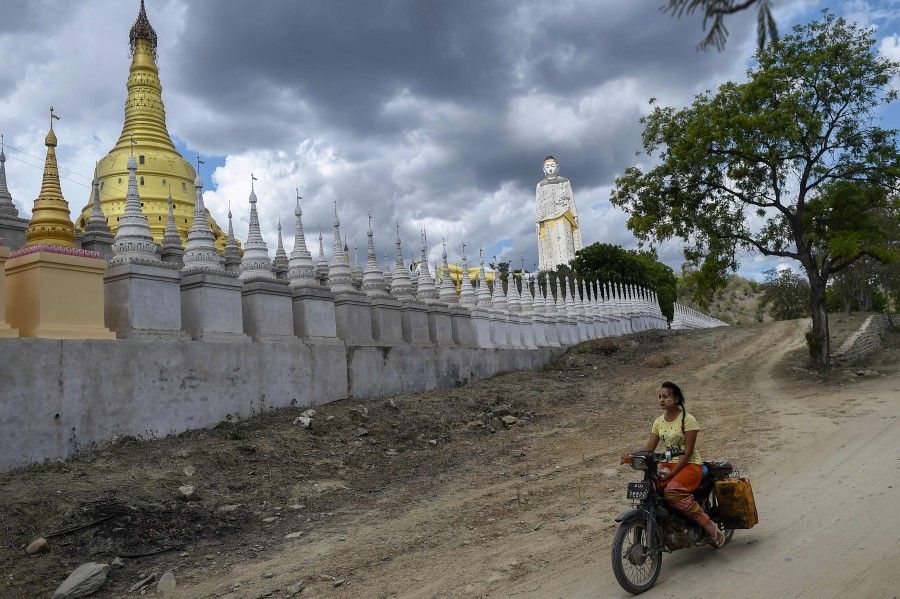 This photo taken on 25 July 2020 shows a girl riding a bike next to Buddhist pagodas in Monywa in the Sagaing region in Myanmar. (Ye Aung Thu/AFP)