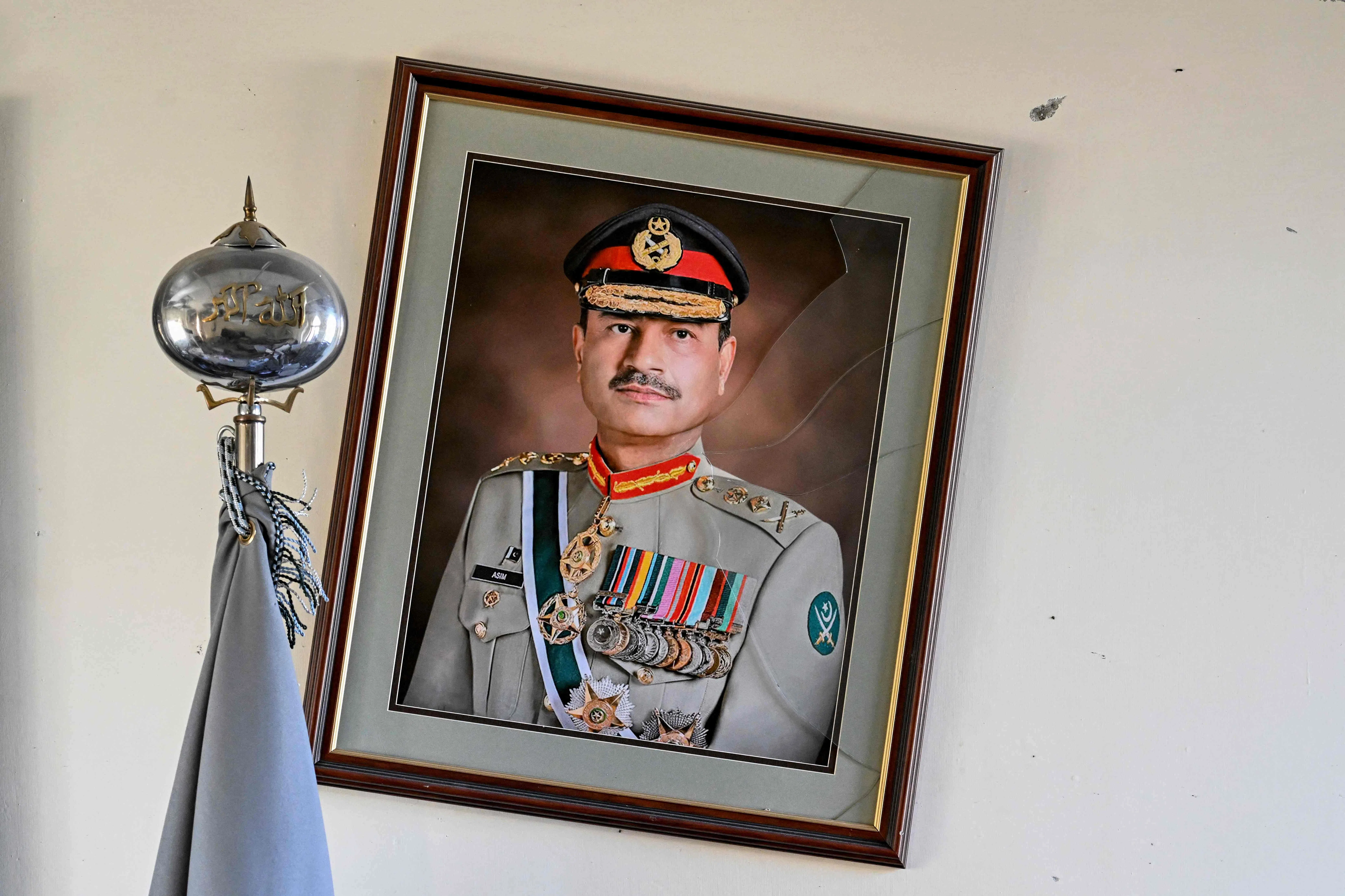 A broken frame of Pakistan's field marshal and army chief, Asim Munir, hangs on the wall after an attack at the Cadet College Wana, a military-linked school, in the South Waziristan district near the Pakistan-Afghanistan border, on 13 November 2025. (Aamir Qureshi/AFP)