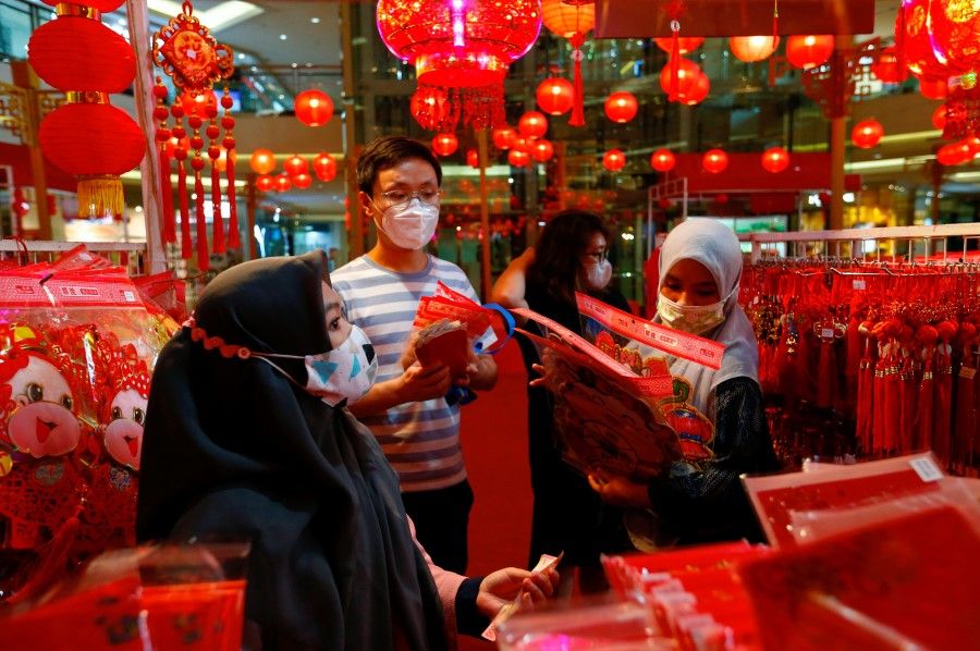 Vendors wearing protective masks serve their customers inside a stall selling decorations, ahead of the Lunar New Year, following the coronavirus disease (Covid-19) outbreak, at a shopping mall in Jakarta, Indonesia, 11 February 2021. (Ajeng Dinar Ulfiana/Reuters)