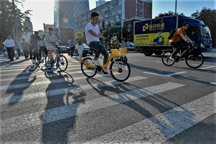 People commute on a street in Beijing, China, on 25 July 2023. (Jade Gao/AFP)