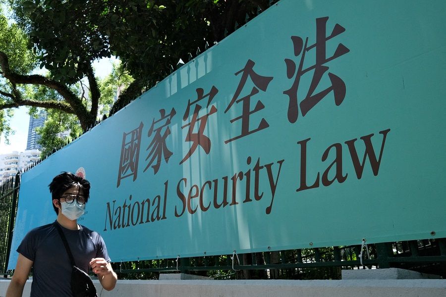 This photo taken on 15 July 2020 shows a man walking past a poster for the National Security Law in Hong Kong. (Anthony Wallace/AFP)