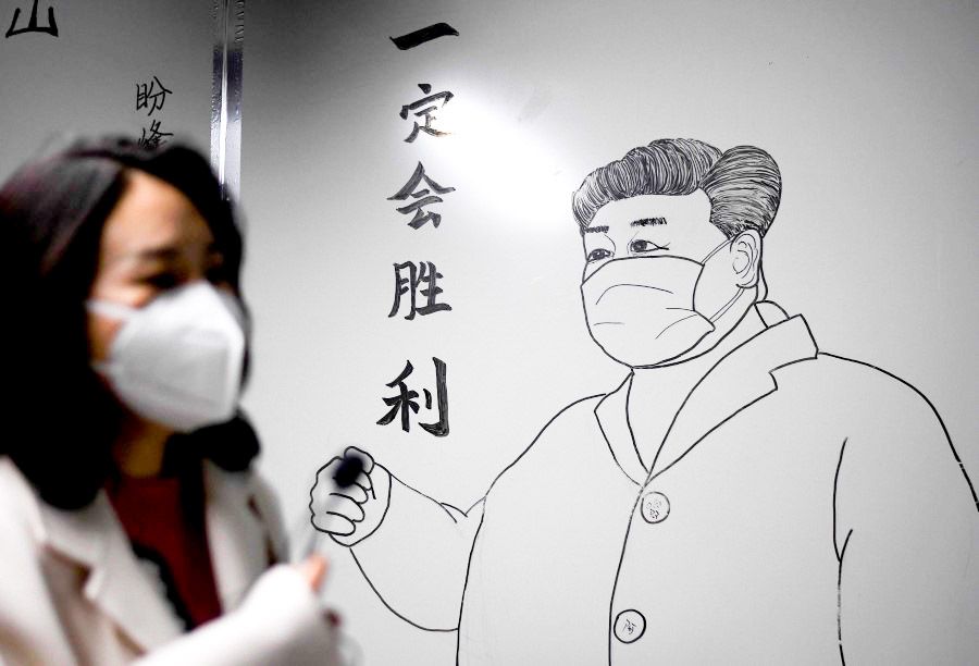 A woman walks in front of a drawing of Chinese President Xi Jinping on a wall at the Leishenshan Hospital that had offered beds for coronavirus patients in Wuhan, April 11, 2020. (Noel Celis/AFP)