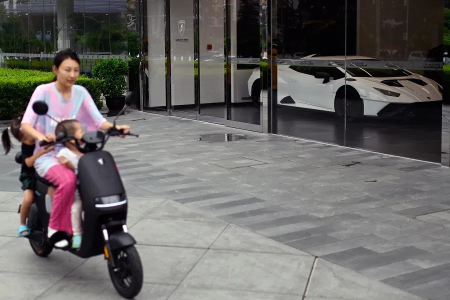 A woman and children ride a scooter in Beijing, China, on 10 September 2023. (Pedro Pardo/AFP)