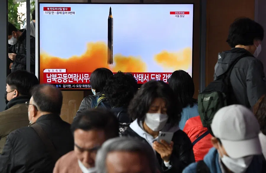 People watch a television screen showing a news broadcast with file footage of a North Korean missile test, at a railway station in Seoul on 13 April 2023. (Jung Yeon-je/AFP)