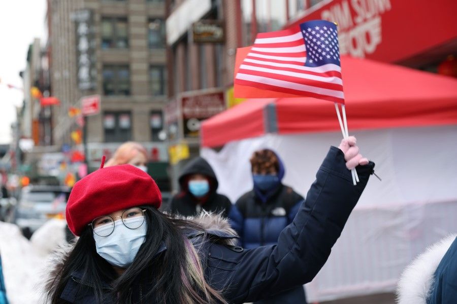 A woman holds the US and China flags at a Lunar New Year ceremony in Chinatown on 12 February 2021 in New York City. (Spencer Platt/AFP)