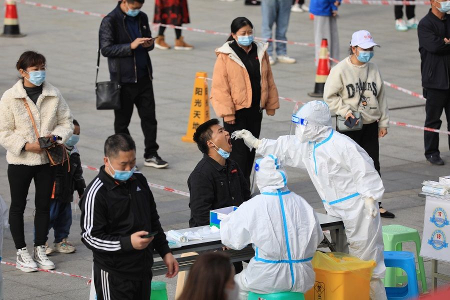 A medical worker in protective suit collects a swab from a man during a mass nucleic acid testing in Huichuan district, Zunyi, Guizhou province, China, 23 October 2021. (CNS photo via Reuters)