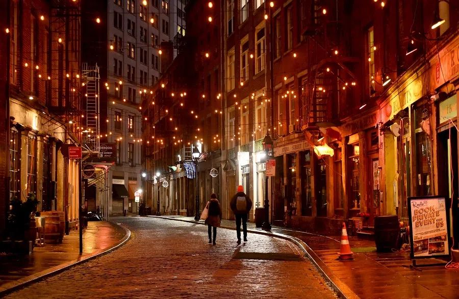 People walk on an empty Stone Street, one of New York's oldest streets, in the financial district of Manhattan on 30 November 2020 in New York City. (Angela Weiss/AFP)
