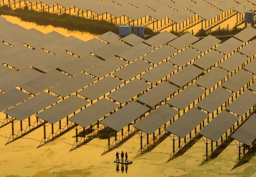 Workers inspect solar panels at the fishing-solar complementary photovoltaic power generation base in Taizhou, Jiangsu province, China, on 12 July 2023. (Stringer/AFP)