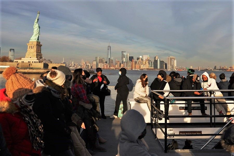People sit on a ferry as the Statue of Liberty, lower Manhattan and One World Trade Center are seen on 5 December 2021 in New York City, US. (Patrick Smith/Getty Images/AFP)