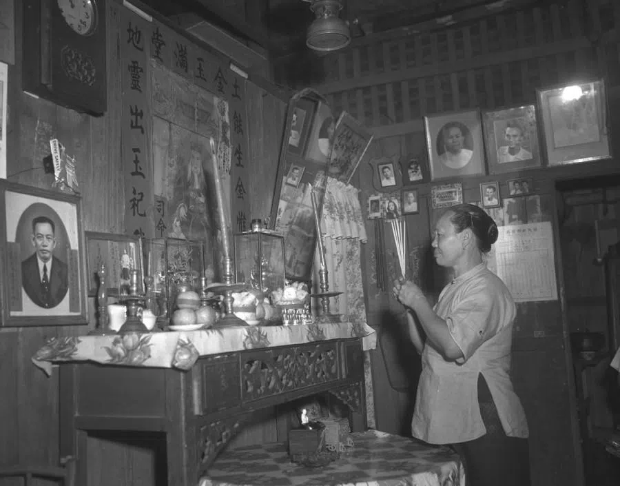 A woman praying in front of a family altar, 3 February 1954. (SPH Media)