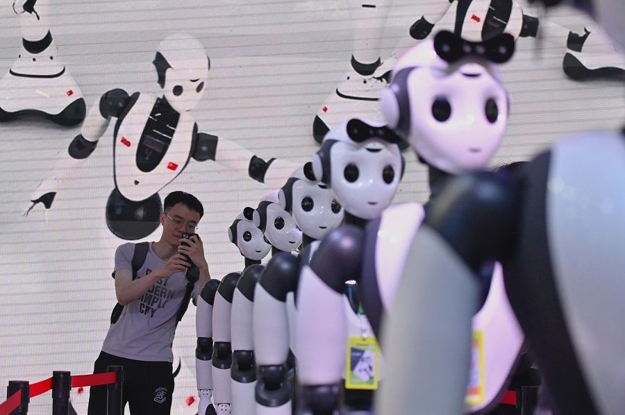 A man takes a picture of robots during the World Artificial Intelligence Conference (WAIC) in Shanghai, China, on 7 July 2023. (Wang Zhao/AFP)