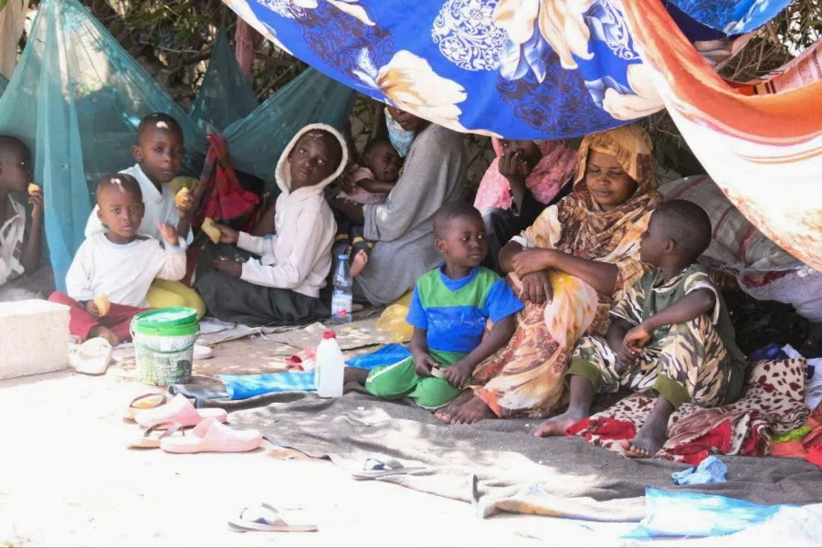 Sudanese families protect themselves from heat and wait with their luggage at a camp center next to Coral Garden Hotel as they call for evacuation to safe countries, following the crisis in Sudan's capital Khartoum, in Port Sudan, Sudan, 14 May 2023. (Ibrahim Mohammed Ishak/Reuters)