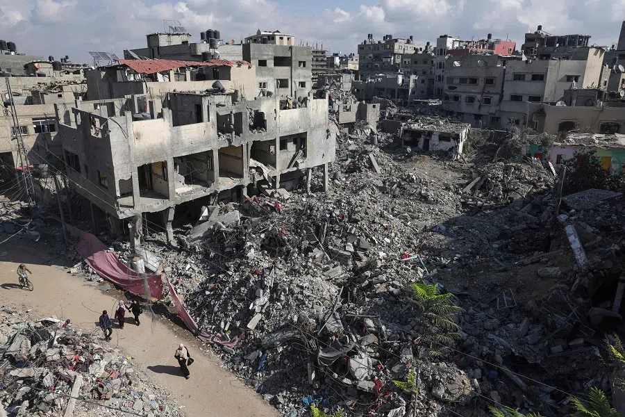 People walk past buildings destroyed following the Israeli bombardment of Gaza, in Bureij, central Gaza Strip, on 14 November 2023. (Mohammed Abed/AFP)