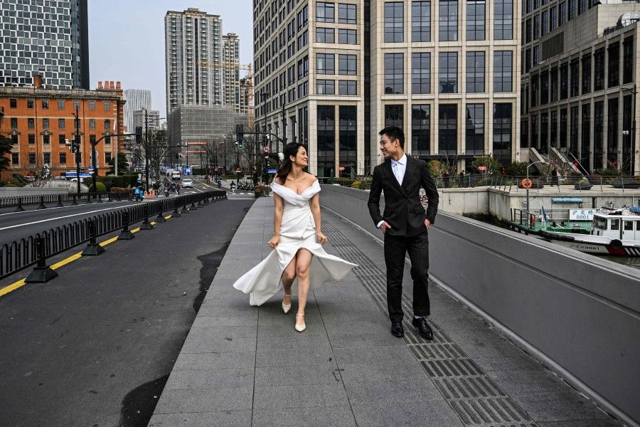 A couple is seen during a pre-wedding photo session on a bridge in Shanghai on 6 March 2024. (Hector Retamal/AFP)