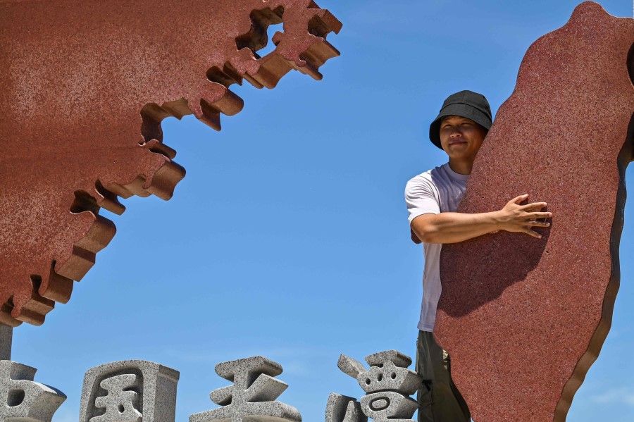 A man poses with a monument representing mainland China (left) and Taiwan (right) on Pingtan island, in Fujian province on 6 August 2022. (Hector Retamal/AFP)