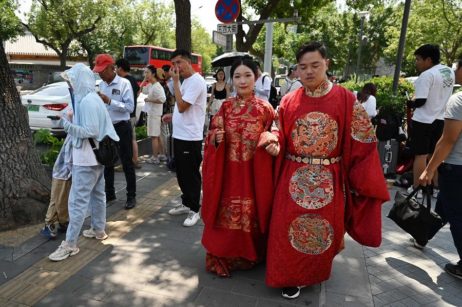 A couple wearing imperial clothing prepare to pose for photos near the Forbidden City during a heatwave in Beijing, China on 24 June 2023. (Greg Baker/AFP)