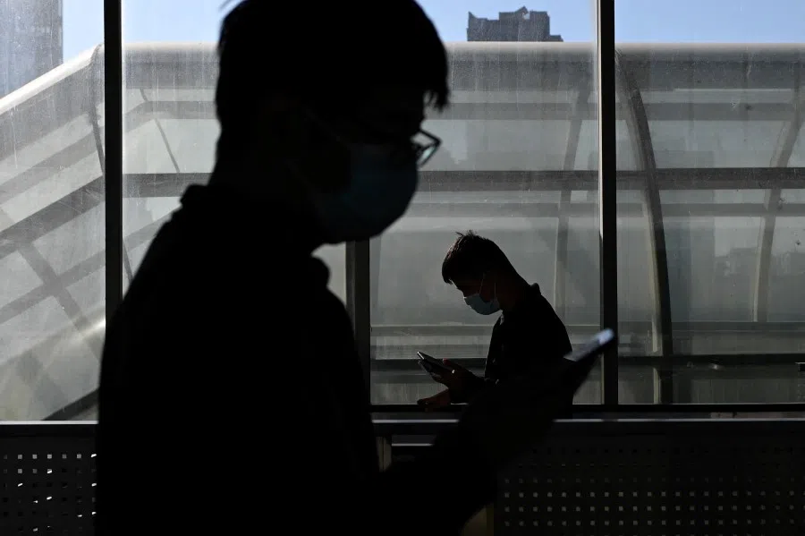 This file photo taken on 23 October 2020 shows people wearing face masks using their mobile phones as they walk out of a subway station in Beijing. (Wang Zhao/AFP)
