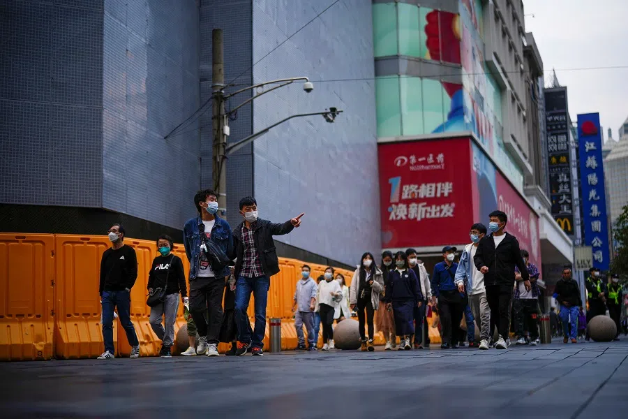 People wear protective masks following the Covid-19 outbreak as they walk on a street in Shanghai, China, 16 October 2022. (Aly Song/Reuters)