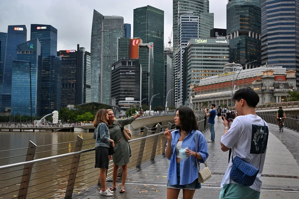 People taking photos at the Jubilee Bridge overlooking the CBD/Raffles Place financial district on 1 March 2023. (SPH Media)