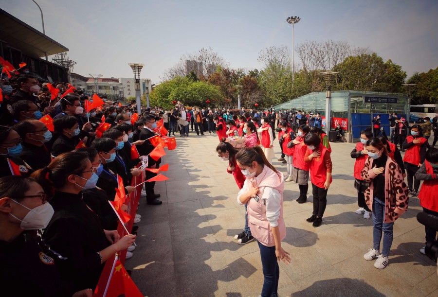 Volunteers from Wuhan thank members of a medical assistance team from Jiangsu province at a ceremony marking their departure after helping with the COVID-19 coronavirus recovery effort in Wuhan, 19 March 2020. (STR/AFP)