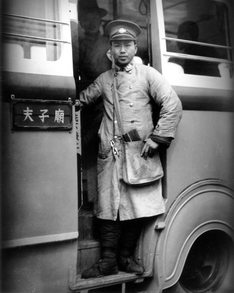 A conductor of a bus to Confucius Temple in Nanjing stands ready to serve with his bag of tickets. During the Six Dynasties period (222-589 AD), the area around Confucius Temple (Wuyi Alley, Zhuque Street, and Taoyedu) was where the well-known families lived.