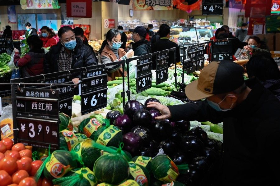 People select vegetables at a supermarket in Beijing on 10 February 2021. (Wang Zhao/AFP)