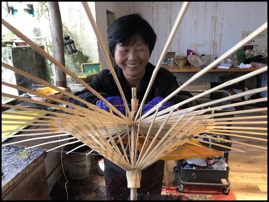 Workshop worker applying paper to a bamboo frame of what will soon become a paper umbrella.