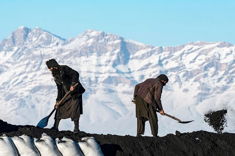 Afghan labourers shovel coal onto a truck bound for Pakistan, at a coal yard on the outskirts of Kabul on 6 January 2025. (Wakil Kohsar/AFP)