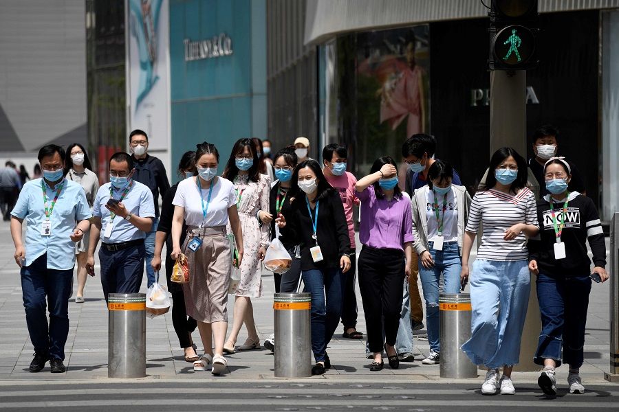 People wearing face masks amid the Covid-19 pandemic cross a street in Beijing on 20 May 2020. (Wang Zhao/AFP)