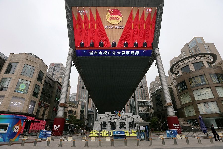A man wearing a face mask walks past a giant screen showing Chinese President Xi Jinping and other leaders at an event celebrating the 100th anniversary of the founding of the Chinese Communist Youth League, amid the Covid-19 outbreak in Beijing, China, 10 May 2022. (Tingshu Wang/Reuters)