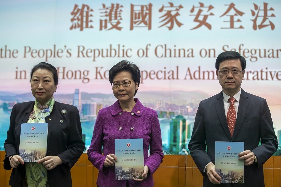 Teresa Cheng, Hong Kong's secretary for justice, from left, Carrie Lam, chief executive and John Lee, secretary for security hold copies of the new national security law at a news conference in Hong Kong, China, on 1 July 2020. (Paul Yeung/Bloomberg)
