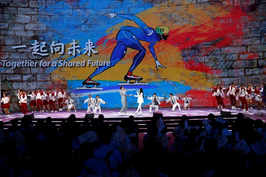 Singers and dancers perform on stage as a giant screen shows the slogan for the Beijing 2022 Winter Games, "Together for a Shared Future", at a ceremony in Beijing, China, 17 September 2021. (Tingshu Wang/Reuters)
