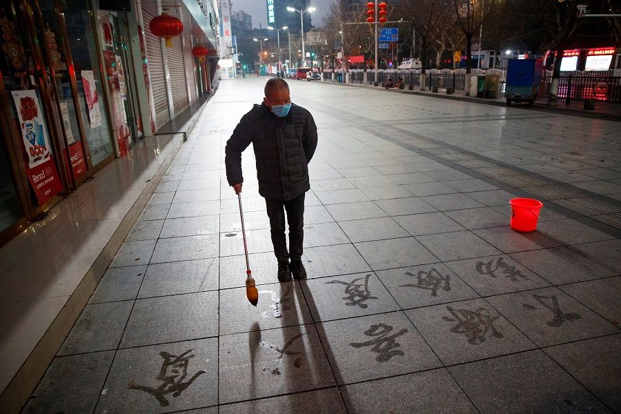 A man wears a face mask as he practices Chinese calligraphy on a pavement amid the Covid-19 pandemic, in Jiujiang, Jiangxi, China, on 3 February 2020. (Thomas Peter/Reuters)