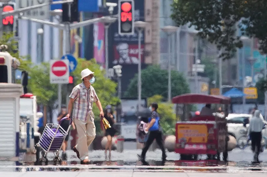 A man wearing a face mask pulls a cart on a street in Shanghai, China, 13 July 2022. (Aly Song/Reuters)