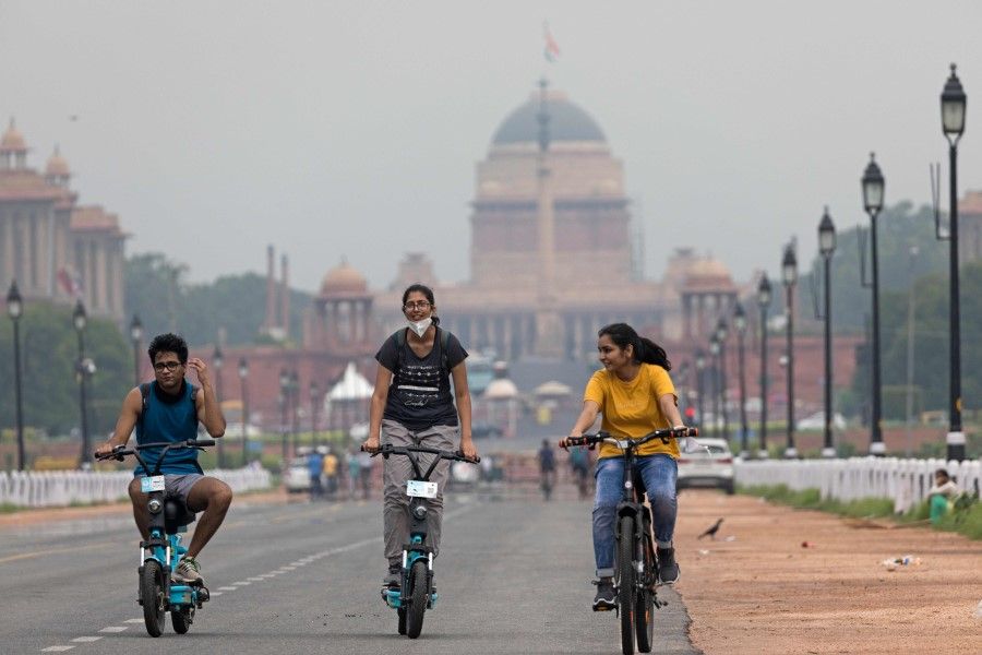 Youths ride electrical scooters and a bicycle along a deserted Rajpath road in New Delhi, 22 July 2020. (Xavier Galiana/AFP)