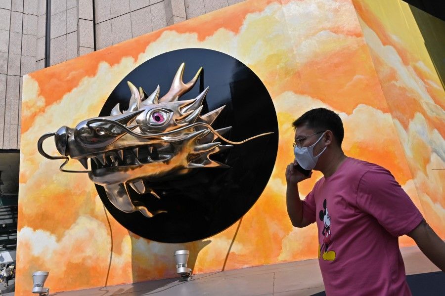 A man wearing a face mask walks past a dragon head decoration outside a mall in Bangkok on 21 January 2021. (Romeo Gacad/AFP)
