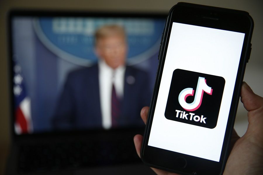 The TikTok logo is displayed in the app store in this photograph in view of a video feed of US President Donald Trump, 3 Aug 2020. (Hollie Adams/Bloomberg)