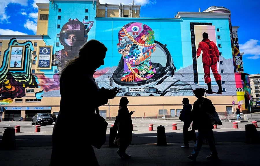 People walk past a shopping mall with giant graffiti on its wall in Moscow, Russia, on 18 May 2022. (Yuri Kadobnov/AFP)
