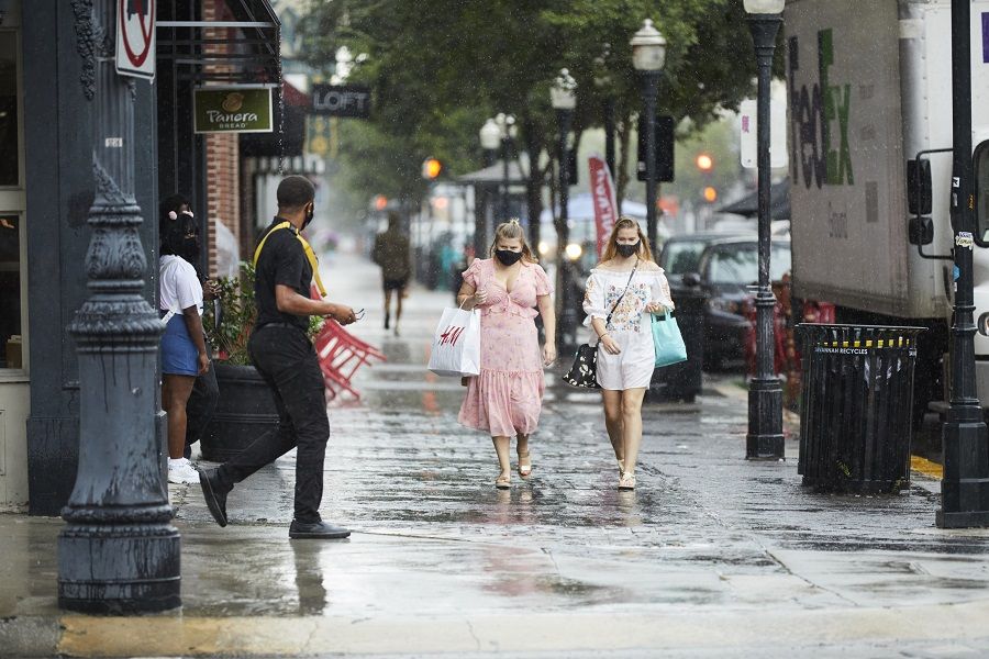 Pedestrians wearing protective masks carry shopping bags while walking along Broughton Street in the rain in Savannah, Georgia, US, on 19 August 2020. (Colin Douglas Gray/Bloomberg)