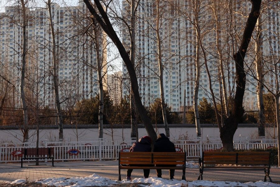 People sit on a bench at a park near residential buildings in Beijing, China, on 15 January 2024. (Florence Lo/Reuters)