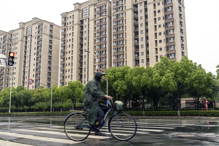 A person cycles past residential buildings in Shanghai, China, on 18 June 2023. (Raul Ariano/Bloomberg)