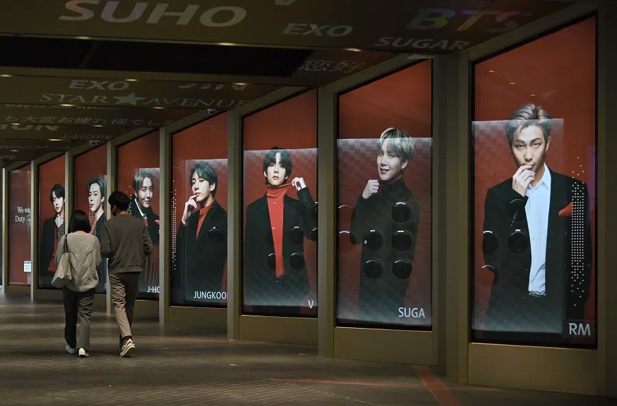 People walk past commercial posters showing K-pop group BTS members outside a duty free shop in Seoul on 6 October 2020. (Jung Yeon-je/AFP)
