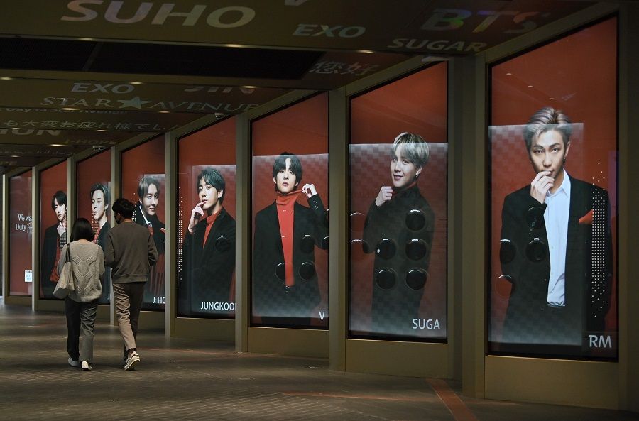People walk past commercial posters showing K-pop group BTS members outside a duty free shop in Seoul on 6 October 2020. (Jung Yeon-je/AFP)