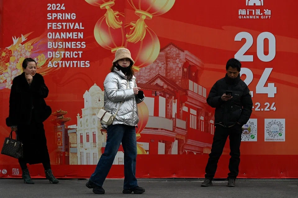 People walk along a shopping street in Beijing on 28 February 2024. (Wang Zhao/AFP)