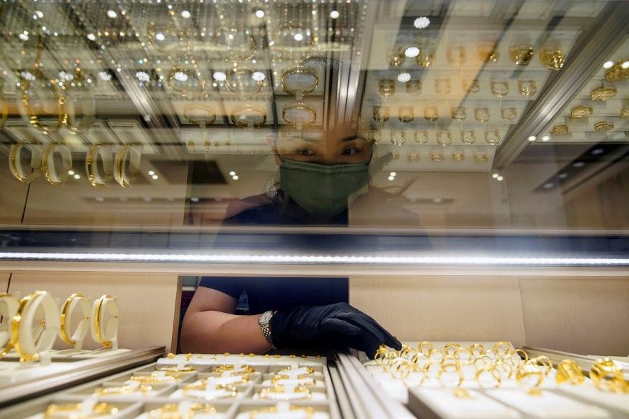 A salesperson poses with gold jewellery at jeweller Chow Tai Fook's retail store in Shanghai, China, 18 August 2021. (Aly Song/Reuters)