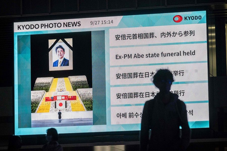 Pedestrians walk past a screen displaying news about the state funeral for Japan's former Prime Minister Shinzo Abe, which took place in Tokyo, Japan, on 27 September 2022. (Yuichi Yamazaki/AFP)