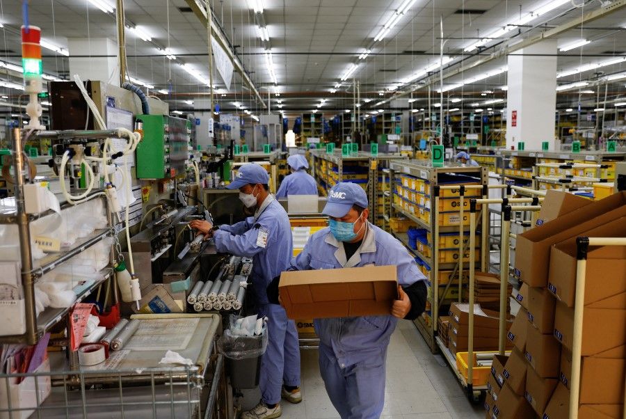 Employees work on a production line manufacturing mechanical parts, amid Covid-19, at a factory of SMC Corporation, during an organised media tour, in Beijing, China, 10 January 2023. (Tingshu Wang/Reuters)